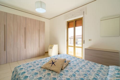 Camera luminosa con biancheria azzurra, armadio in legno, vista mare e comfort moderni a Marina di Strongoli