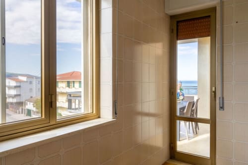 Luminoso appartamento con vista mare a Marina di Strongoli, porta in vetro verso terrazza arredata e edifici costieri