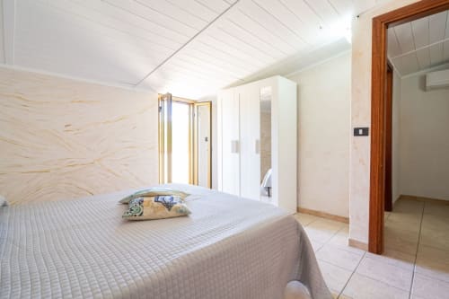 Camera luminosa con letto, guardaroba bianco e balcone con vista sul mare presso l'appartamento in prima linea Lux Immobiliare a Marina di Strongoli,