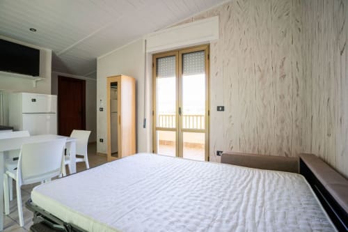 Camera da letto luminosa con vista mare a Marina di Strongoli, letto matrimoniale, angolo cottura, tavolo e accesso al balcone