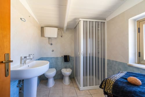 Bagno moderno nell'appartamento di Marina di Strongoli con lavabo, wc, bidet, doccia e camera da letto sullo sfondo