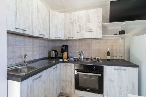 Cucina moderna con mobili bianchi, piano cottura a gas, lavello e top neri in appartamento fronte mare a Marina di Strongoli