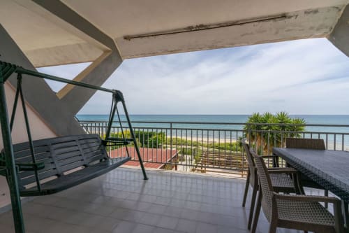 Balcone fronte mare di Lux Immobiliare con vista sul mare, altalena, tavolo da pranzo e palme a Marina di Strongoli