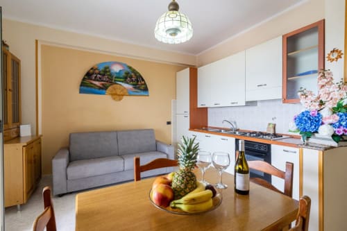 Moderno appartamento con vista mare a Marina di Strongoli, cucina aperta, tavolo da pranzo, divano grigio e fiori freschi