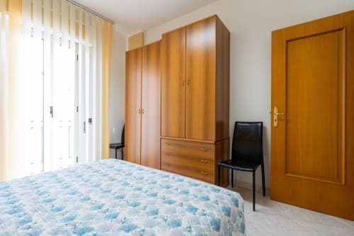 Ampia camera da letto con armadio in legno, letto a motivi blu e vista mare presso Lux Immobiliare, Marina di Strongoli