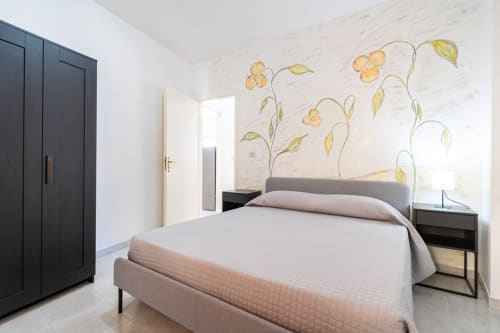 Camera da letto moderna con vista sul mare a Lux Immobiliare, Marina di Strongoli. Letto matrimoniale, armadio nero, murale floreale, luminosa