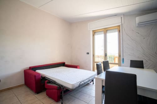Divano letto rosso con materasso bianco nell'appartamento fronte mare di Marina di Strongoli, tavolo da pranzo e balcone con vista sul mare