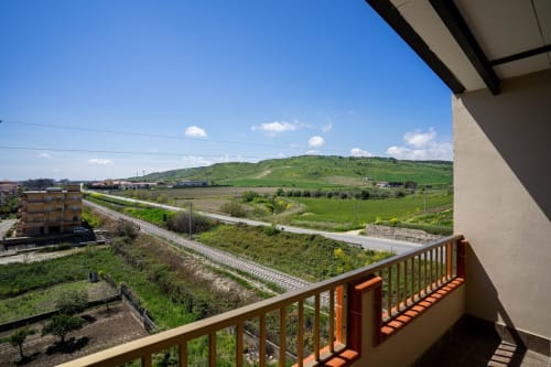 Vista dal balcone di Lux Immobiliare a Marina di Strongoli, con panorama su colline verdi, binari ferroviari e paesaggio costiero