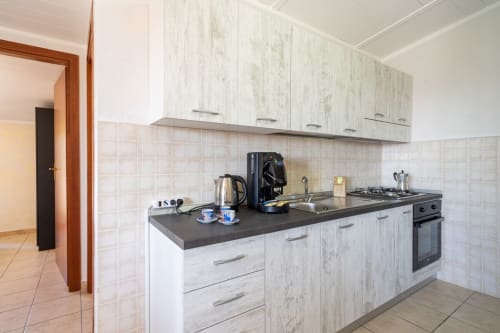 Cucina moderna con ante in legno bianco e piano di lavoro scuro nell'appartamento fronte mare di Lux Immobiliare a Marina di Strongoli,
