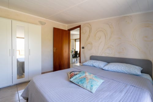 Ampia camera da letto presso il BnB Marina di Strongoli con letto matrimoniale, carta da parati con vista mare, guardaroba bianco e comfort moderni