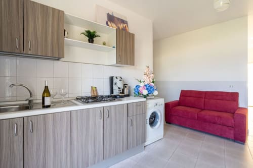 Cucina moderna con divano rosso nell'appartamento fronte mare di Marina di Strongoli, con elettrodomestici in acciaio inossidabile e vista sul mare