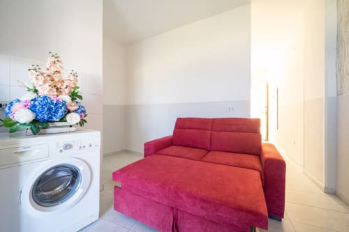 Divano letto rosso nell'appartamento Marina di Strongoli con lavatrice, fiori e vista sul mare