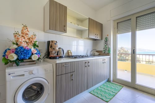 Cucina moderna con vista mare al Marina di Strongoli BnB, con mobili in legno, cucina a gas e accesso al balcone costiero