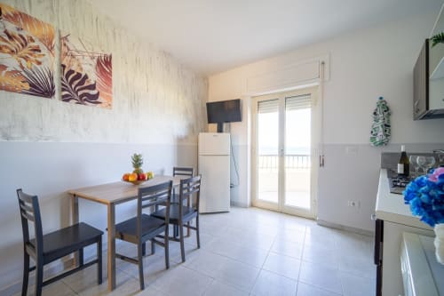 Moderna zona cucina-pranzo nell'appartamento di Marina di Strongoli con vista mare, pareti bianche, tavolo da pranzo e vetrate