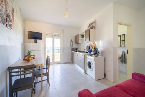 Cucina e soggiorno moderni con vista sul mare a Marina di Strongoli, con tavolo da pranzo, elettrodomestici e dettagli rossi