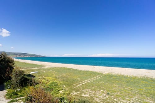 Acque turchesi del Mediterraneo e spiaggia sabbiosa a Marina di Strongoli con paesaggio costiero verde e cielo azzurro limpido