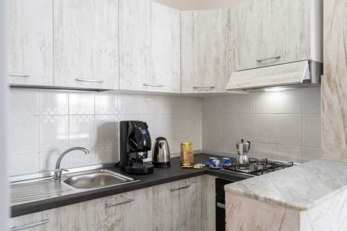 Cucina moderna nell'appartamento di Marina di Strongoli con mobili bianchi, piano nero, elettrodomestici acciaio inox e gas
