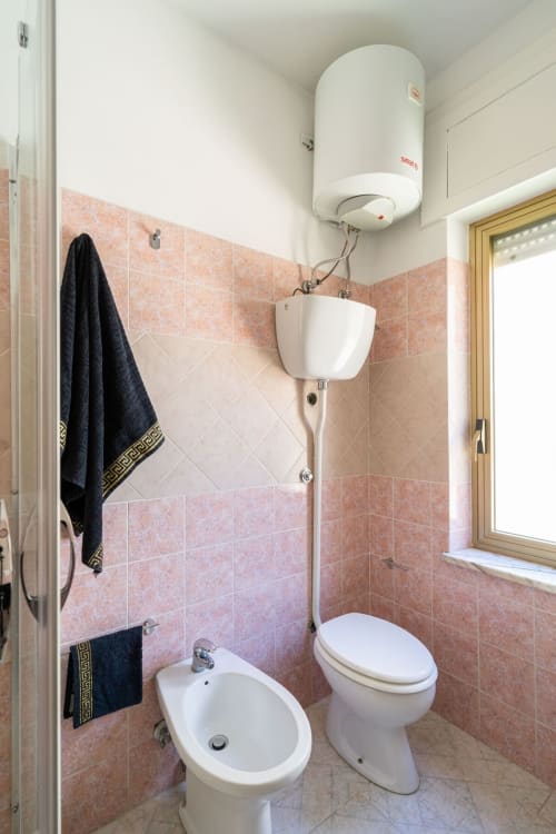 Bagno dell'appartamento a Marina di Strongoli con bidet, WC, lavabo sospeso e scaldabagno elettrico