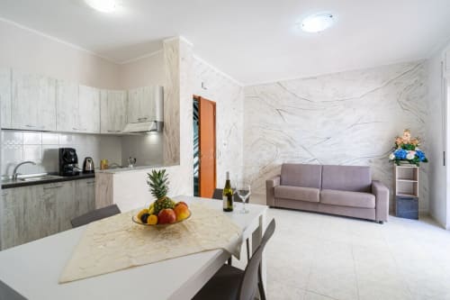 Moderno appartamento open-plan a Marina di Strongoli con cucina, tavolo da pranzo e soggiorno con vista mare e divano viola