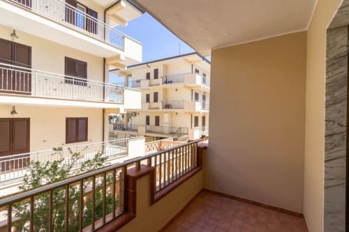 Balcone soleggiato con vista sulla corte dell'appartamento fronte mare a Marina di Strongoli, ringhiere moderne e terracotta