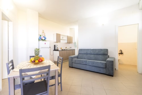 Appartamento open space fronte mare a Marina di Strongoli con tavolo da pranzo, divano blu, cucina e accesso alla vista sul mare