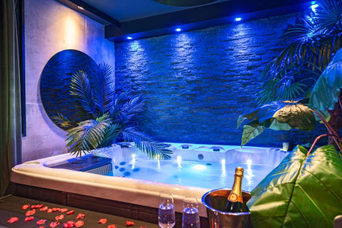 Luxueux bain à remous avec éclairage bleu et plantes tropicales à L'Insolite Spa Privatif à Toulouse