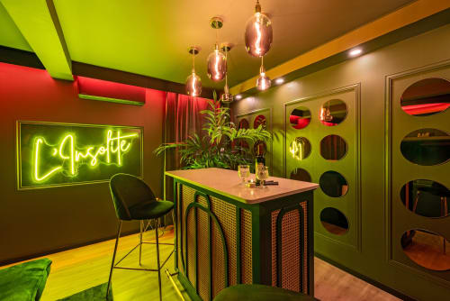 Bar lounge contemporain néon à L'Insolite Spa Privatif Toulouse, accents vert citron, luminaires suspendus et miroir circulaire