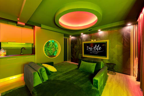 Suite spa moderne à L'Insolite à Toulouse avec murs vert anis, plafond luminescent, mobilier en velours vert et néons