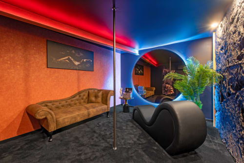 Élégant salon VIP au L'Insolite Spa de Toulouse avec canapé en velours doré, éclairage néon et sculpture contemporaine noire