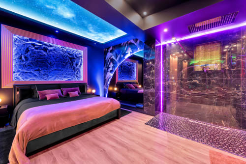 Chambre de luxe moderne à L'Insolite Spa Privatif à Toulouse avec murs néon, lit king-size et baignoire chauffée vitrée