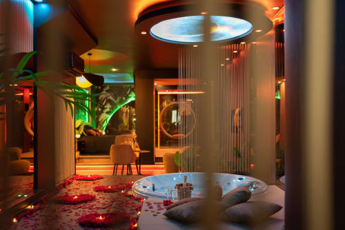 Salle de bain spa luxueuse avec lucarne circulaire illuminée, pétales de rose, bougies et baignoire moderne à L'Insolite Toulouse