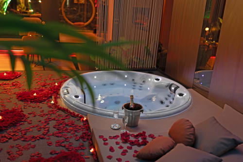 Jacuzzi luxe d'un spa avec pétales de rose, champagne et éclairage romantique à L'Insolite, Toulouse
