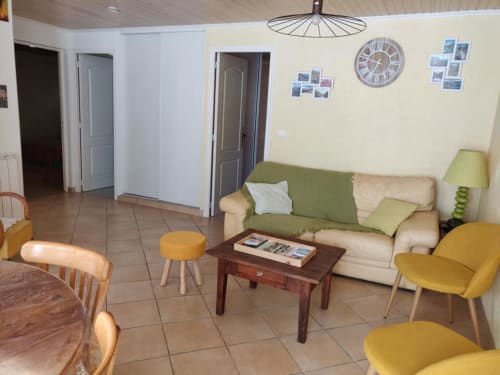 Lumineux séjour avec canapé vert et beige, chaises jaunes, table basse en bois et vue sur les montagnes à MarjoRI