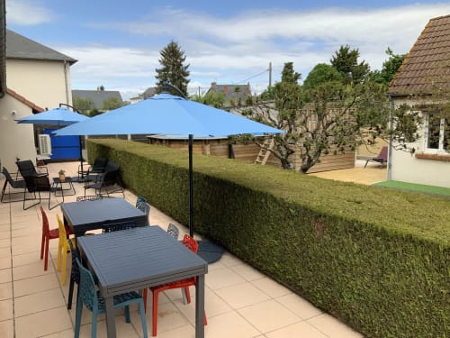 Blois cottage garden patio with blue umbrellas, dining tables, and hedges