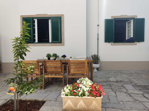 Pátio da Villa Sor em Ponte de Sor com assentos de madeira, floreiras coloridas e janelas com venezianas verdes
