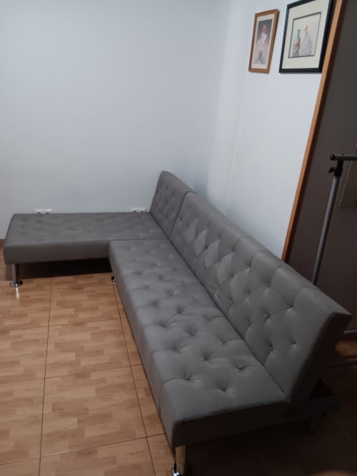 Gray tufted sofa in modern room at Casa Ferrer Barcelona with wooden flooring and framed artwork