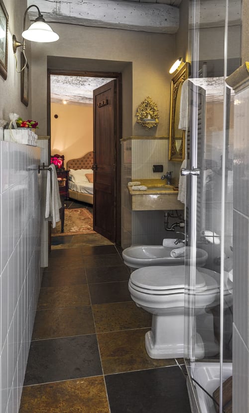 Salle de bain élégante de la Chambre Deluxe Le Camelie à Dimora i Manichei, Monforte d'Alba, avec doubles toilettes et vanité