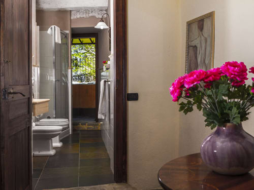 Salle de bain lumineuse avec fleurs roses dans un vase violet, Chambre Le Camelie Deluxe à Dimora i Manichei, Monforte d'Alba