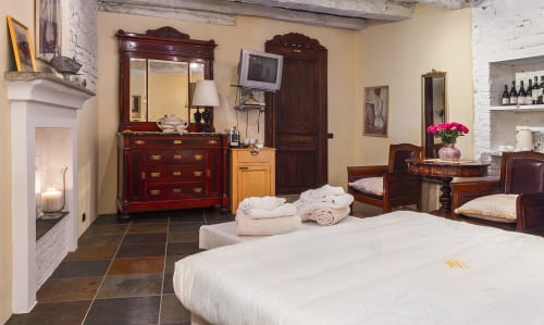 Spacieuse chambre de luxe à la Dimora i Manichei B&B à Monforte d'Alba avec lit, cheminée, mobilier en bois foncé et linges blancs