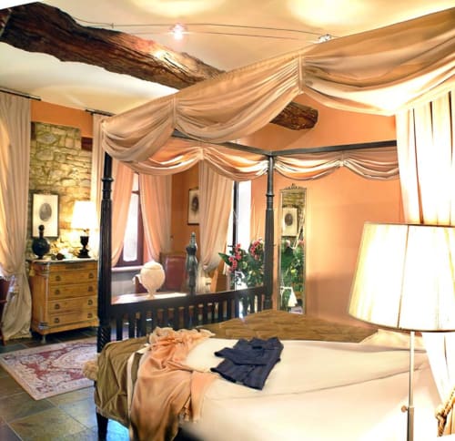 Elegant canopy bed in Apartment Le Rose at Dimora i Manichei, Monforte d'Alba, with terracotta walls and draped curtains