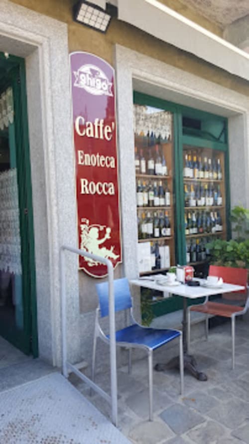 Ingresso di Caffè Enoteca Rocca a Dimora i Manichei, Monforte d'Alba, con esposizione di vini e tavoli all'aperto