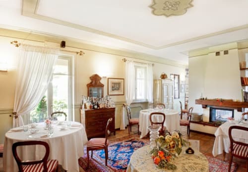 Elegante sala da pranzo di Dimora i Manichei a Monforte d'Alba con tavoli rotondi, mobili in legno e arredamento classico italiano