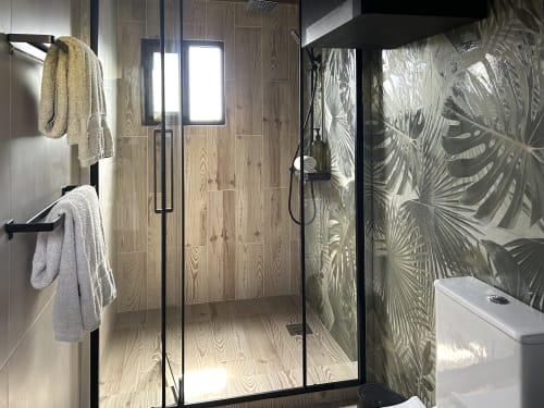 Modern bathroom shower with wood-look tile walls and decorative glass doors at Villa Várzea, a mountain-view bed & breakfast