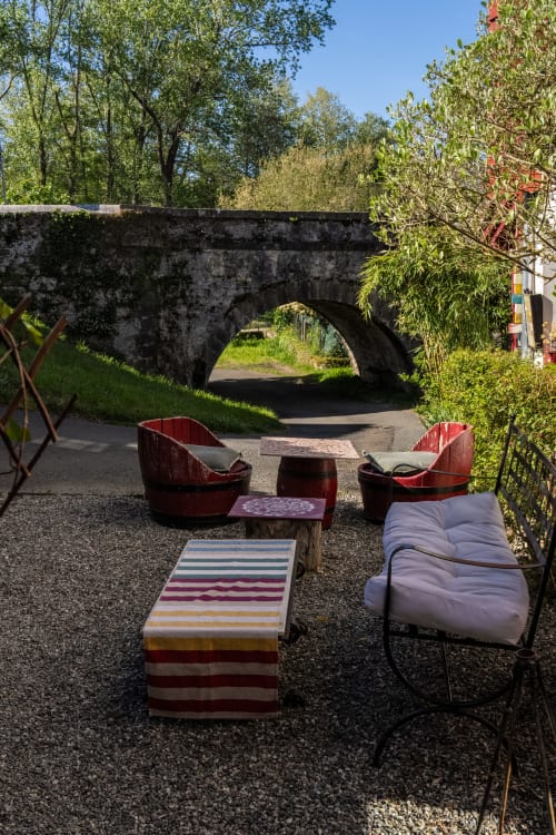space lounge insolite au Moulin de Pascale avec fauteuils tonneaux rouges face au pont de pierre historique d'Espelette.