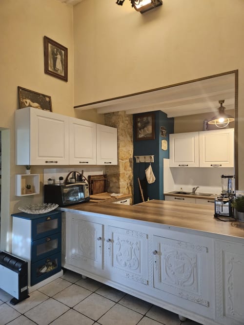 Moderne Küche in der Suite Le Manoir Lacustre mit weißen Schränken, Holzarbeitsplatte und blauem Akzentwand in Queyrac, Frankreich