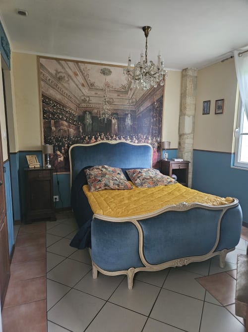Elegantes blaues Polsterbett mit gelbem Steppdecke im Le Manoir Lacustre Suite mit ornamentalem Kristalllüster