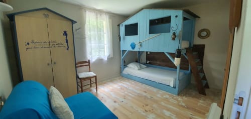 Buntes Kinderzimmer im Manoir Lacustre mit blauem Baumhausbett und gelbem Kleiderschrank, Gartenfenster, Holzausstattung