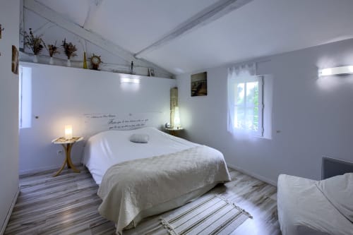 Helles Schlafzimmer im Le Manoir Lacustre mit Queensize-Bett, weißer Bettwäsche, Fenster mit Gartenblick und modernem Komfort