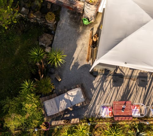 Vue aérienne de la grande terrasse aménagée avec barnum blanc et mobilier coloré, idéale pour se détendre au soleil.