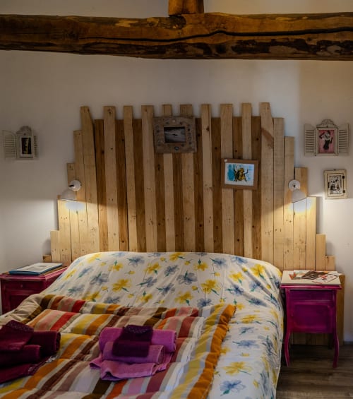 Chambre d'hôtes Banca à Espelette : lit double sous poutres apparentes séculaires, tête de lit artisanale et armoire de charme au Pays Basque.